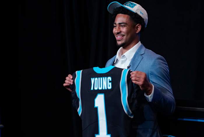 Bryce Young holds up a jersey depicting his draft position at Bank of America Stadium.